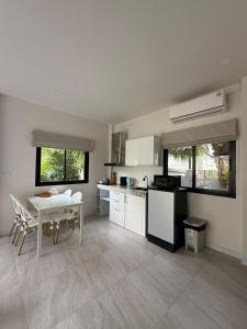a white kitchen with a table and a table and chairs at Srithanu Escape 1 in Srithanu