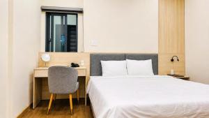a bedroom with a bed and a desk with a chair at New Star Hotel Tay Ninh in Tây Ninh