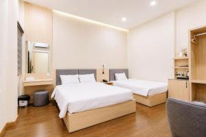 a hotel room with two beds and a chair at New Star Hotel Tay Ninh in Tây Ninh