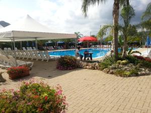 a person sitting at a table next to a swimming pool at Le Ville di Porto Ada in Pizzo