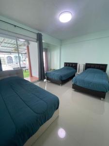 two beds in a bedroom with blue sheets and a window at 55 Hostel Soi Phetkasem 51 in Ban Tambon Bang Khae