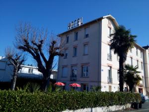 un edificio blanco con palmeras delante en Hôtel du Parc, en Salies-du-Salat