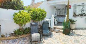 a patio with three chairs in front of a building at El Rincón del Sotillo beach in Los Alcázares