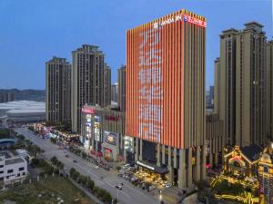 a tall red building in a city with buildings at Wanda JIN Baise in Qitang