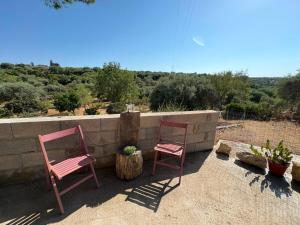 two pink chairs sitting next to a wall at Blue Sky Sardinia in Sorso