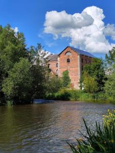 an old brick building next to a body of water at La Cabane du Noyer in Morée