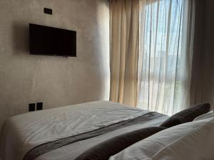 a bedroom with a bed and a television on the wall at Casa Mayab in León
