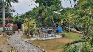 a person standing in a garden with a table and chairs at dilo tree lodge in Sigatoka +2 photos