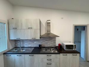 a kitchen with a stove top oven next to a microwave at Blue Sky Sardinia in Sorso +8 photos