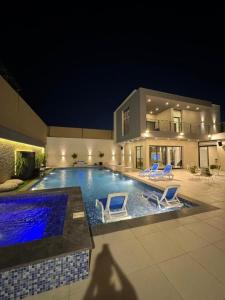 a swimming pool with two blue chairs and a house at تجريبي in Şan‘āʼ