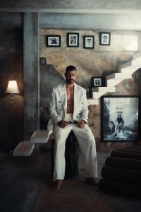 a man in a white suit sitting on a chair at The Corduroy Hotel in Canggu
