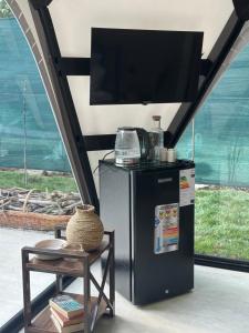 a television on top of a refrigerator next to a table at Ugam Glamping in Khumson