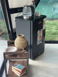 a small refrigerator next to a table with books at Ugam Glamping in Khumson