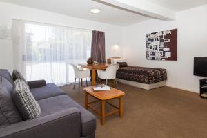 een woonkamer met een bank en een tafel bij Casino Court Motor Lodge in Christchurch