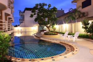 a swimming pool with two chairs and a table in front of a building at Phu View Talay Resort in Pattaya South