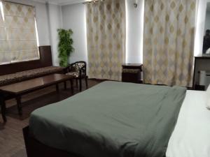 a bedroom with a bed and a couch and a table at Hotel Ienvo Inn in New Delhi