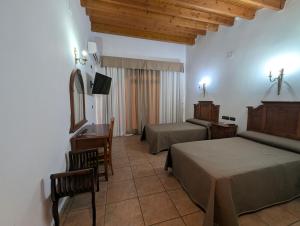 a bedroom with two beds and a desk and a mirror at Hotel Alfonso VIII in Santa Elena