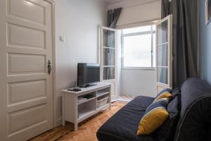 uma sala de estar com um sofá e uma televisão em Apartamento junto à Fonte Luminosa em Lisboa