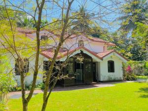 a pink and white house with a green yard at Kudaarala Heritage in Kengalla