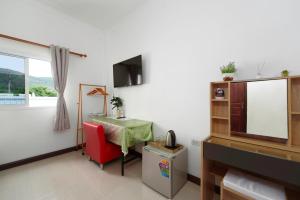 a living room with a red chair and a television at Passion Nai Harn Guesthouse in Nai Harn Beach