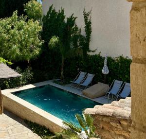 a swimming pool with two lawn chairs next to a building at Le Numéro 10 in Bernis