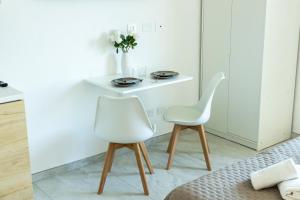 two white chairs and a table in a room at Comfyrooms in Quartu SantʼElena