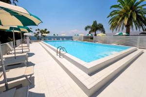 a swimming pool with two chairs and an umbrella at Hotel Delfino Taranto in Taranto