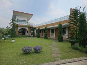 a large house with a yard with purple flowers at Charming Home Resort in Suan Phung