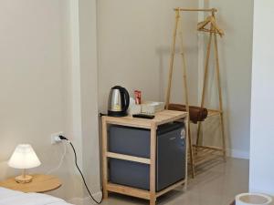a room with a table with a microwave and a lamp at Charming Home Resort in Suan Phung