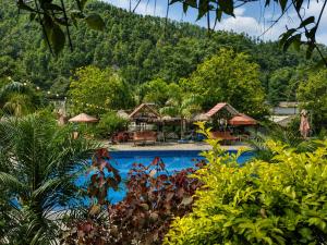 a resort swimming pool with a mountain in the background at Sukute River Hub Beach Resort in Dolālghāt