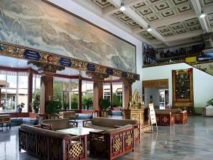 a lobby with couches and a large painting on the wall at Lhasa Hotel in Lhasa