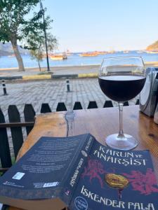 a glass of wine sitting on a table next to a book at Adrasan blue bay hotel in Kumluca