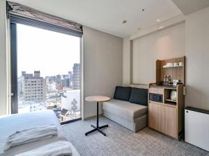 a bedroom with a bed and a desk and a window at Meitetsu Inn Nagoyaeki Shinkansenguchi in Nagoya