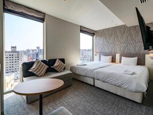 a hotel room with a large bed and a couch at Meitetsu Inn Nagoyaeki Shinkansenguchi in Nagoya