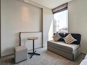 a room with a chair and a table and a window at Meitetsu Inn Nagoyaeki Shinkansenguchi in Nagoya