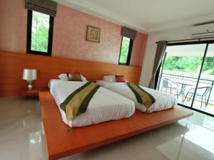two beds sitting in a room with a wooden wall at Phakawan Hotel in Ban Nong Chik