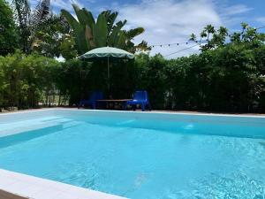 a swimming pool with a table and an umbrella at The State Resort in Ban Wat Phrik (1)