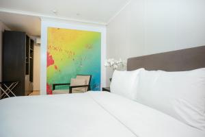 a bedroom with a white bed and a painting at Green Sun Hotel in Manila +25 photos