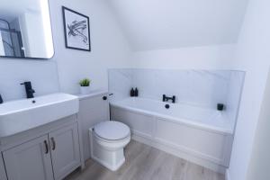 a white bathroom with a toilet and a tub and a sink at Harbourside, Shetland Islands in Lerwick