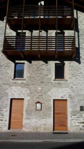 a building with three doors and a balcony at hortus conclus in Piuro +4 photos