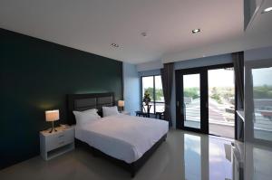 a bedroom with a white bed and a green wall at Sixty-Sixplace in Ban Khok Lo