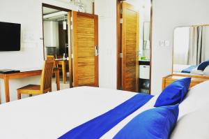 a bedroom with a bed with blue pillows and a desk at Airport Comfort Inn Premium in Hulhumale