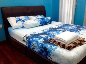 a bed with blue and white sheets and pillows at Villa Sri Tebengau in Kuah