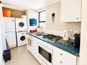 a kitchen with white cabinets and a stove top oven at Sandy Fingers Apartment in Plettenberg Bay