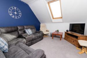 a living room with a couch and a clock on the wall at North Harbour View, Shetland Islands in Lerwick