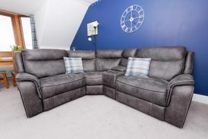 a brown leather couch in a living room with a clock at North Harbour View, Shetland Islands in Lerwick +24 photos