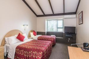 a hotel room with two beds and a flat screen tv at Dupont Motels in Lower Hutt