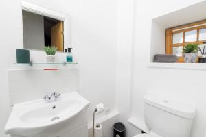 a white bathroom with a sink and a toilet at Mowbray's Nook, Shetland Islands in Lerwick