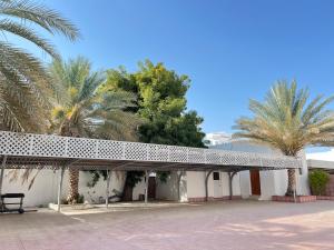 a white building with palm trees and a bench at Waterfront vip master room in Muscat