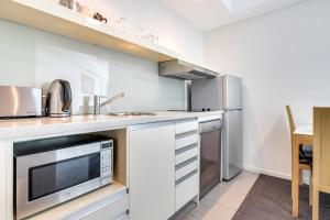 a kitchen with a sink and a microwave at 18th Floor Seaview Executive Style King Bed with Pool and Gym in Darwin